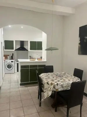 a kitchen with a table and a kitchen with green cabinets at Centrale - Grand T2 Bis proche de la mer in Nice