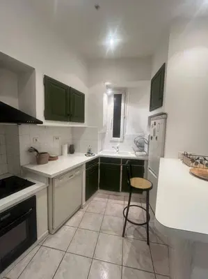 a kitchen with green cabinets and a chair in it at Centrale - Grand T2 Bis proche de la mer in Nice