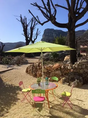 a table and chairs under a yellow umbrella on the beach at Maison de caractère in Saint-Jeannet