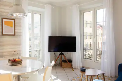 a living room with a television and a table with chairs at #13 Orange suite AC Wifi Balcony 3mins walk sea front in Nice