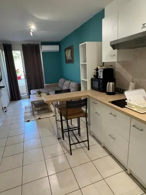 a kitchen with a table and a living room at Logement proche de la plage in Nice
