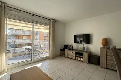 a living room with a flat screen tv and a balcony at Nice Proche Mer in Nice