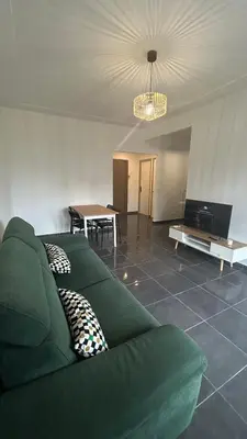 a living room with a green couch and a table at oliveraie in Nice
