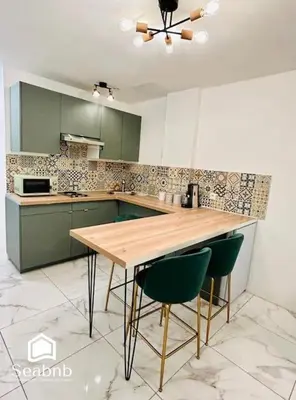a kitchen with a wooden table and two green chairs at Charming Downtown - AC - WiFi - Private Entrance in Nice