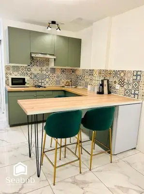 a kitchen with a wooden counter and two green chairs at Charming Downtown - AC - WiFi - Private Entrance in Nice