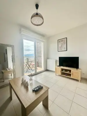 a living room with a television and a table at Cosy studio avec parking et vue féerique in Nice