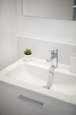a white bathroom sink with a plant on it at Magnifique 3 pièces de 80m2 dans le Carré d'Or in Nice