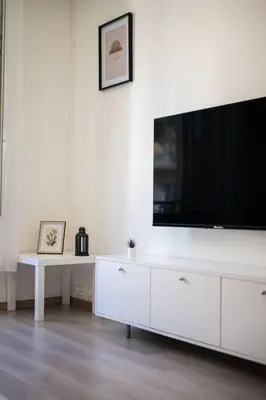 a white living room with a large flat screen tv at Magnifique 3 pièces de 80m2 dans le Carré d'Or in Nice