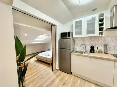 a kitchen with a refrigerator and a bed in a room at Appartement climatisé - 2min plage-tram-restaurant in Nice