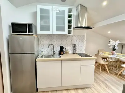 a kitchen with white cabinets and a refrigerator at Appartement climatisé - 2min plage-tram-restaurant in Nice
