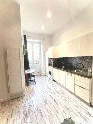 a kitchen with white cabinets and a wooden floor at Malyandco in Nice
