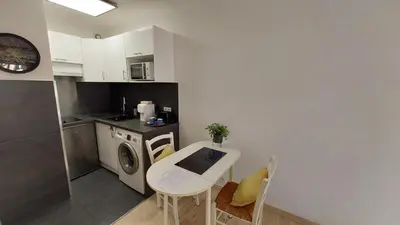 a small kitchen with a table and a washing machine at Studio piscine climatisation tennis in Nice