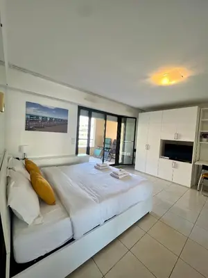 a large white bedroom with a large bed with yellow pillows at Studio Palais de la Méditerranée in Nice