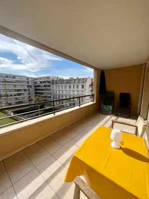 a balcony with a yellow table and a view of a building at Studio Palais de la Méditerranée in Nice
