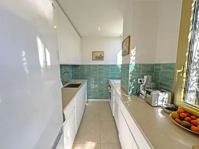 a kitchen with white cabinets and green tiles at Cosy Sea Front Garden Nice in Nice