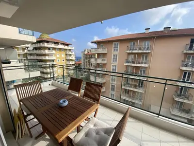 a balcony with a wooden table and chairs on a balcony at Nice Magnan 2P-Piscine, Clim, Parking in Nice