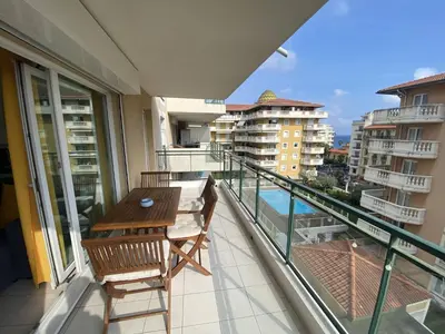 a balcony with a wooden table and chairs on a balcony at Nice Magnan 2P-Piscine, Clim, Parking in Nice