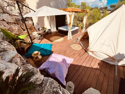 a wooden deck with a white umbrella and a table at LOVE ROOM Tente chauffée Lodge spa MFG chez C&C, exclusivement réservée aux ADULTES in Cantaron