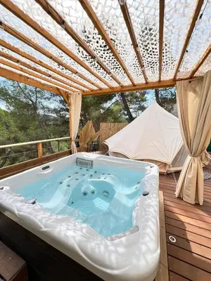 a hot tub on a deck with a roof at LOVE ROOM Tente chauffée Lodge spa MFG chez C&C, exclusivement réservée aux ADULTES in Cantaron