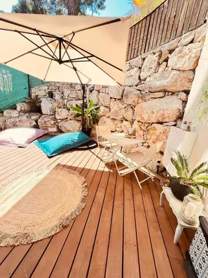 a patio with an umbrella and chairs on a wooden deck at LOVE ROOM Tente chauffée Lodge spa MFG chez C&C, exclusivement réservée aux ADULTES in Cantaron