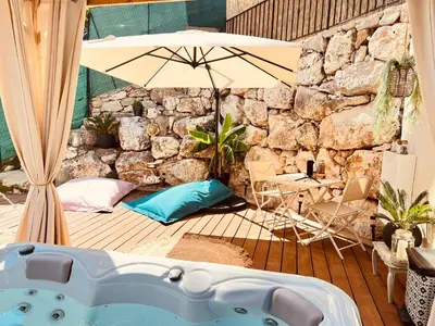 a hot tub on a deck with an umbrella at LOVE ROOM Tente chauffée Lodge spa MFG chez C&C, exclusivement réservée aux ADULTES in Cantaron