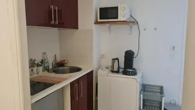 a small kitchen with a microwave on top of a refrigerator at Petit studio promenade des Anglais in Nice
