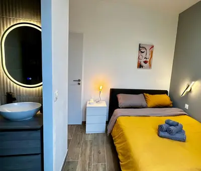 a bedroom with a yellow bed and a sink at Chic Renovated Home - Nice Libération - Entire 2BR 2BA Apartment or Private Rooms with Private Bathrooms - AC and Garage on request in Nice