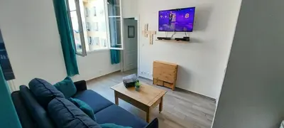 a living room with a blue couch and a tv at Charmant 2 pièces in Nice