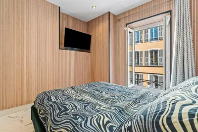 a bedroom with a bed and a tv and a window at Nice Renting - 7FRANCE - Suite Luxe & Confort Bord de Mer Massena in Nice