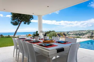 a white table with chairs and a view of the ocean at VILLA ADRIANA VI4411 By Riviera Holiday Homes in Nice