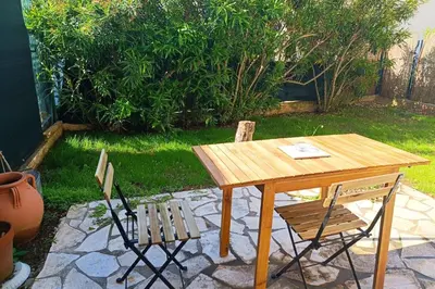 a wooden table and two chairs sitting next to a patio at Refurbished apartment with terrace and garden in Nice
