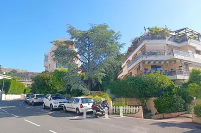 a parking lot with cars parked in front of a building at Refurbished apartment with terrace and garden in Nice