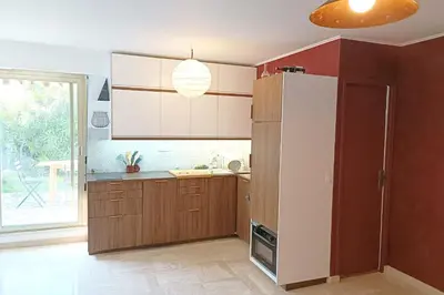 a kitchen with brown cabinets and a white refrigerator at Refurbished apartment with terrace and garden in Nice
