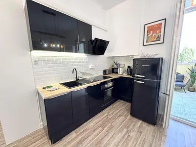 a kitchen with black cabinets and a black refrigerator at ApartHotel Riviera - TERRASSE HORIZON - 15' Promenade des Anglais in Nice