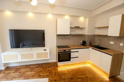 a kitchen with white cabinets and a tv on the wall at Nice carré d'or proche Negresco in Nice