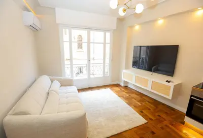 a living room with a white couch and a tv at Nice carré d'or proche Negresco in Nice