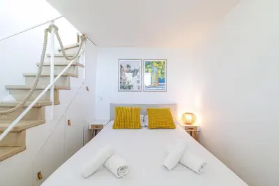 a white bedroom with a bed with yellow pillows at 73 CORNE D OR - Duplex plein SUD, VUE MER, BALCON in Villefranche-sur-Mer