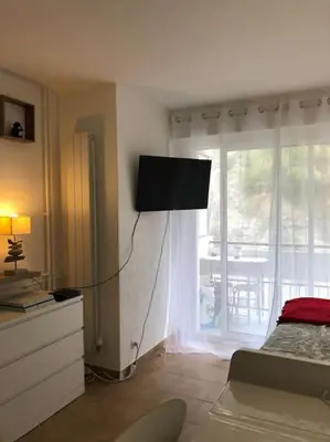 a bedroom with a bed and a television on the wall at Le Rabelais, Studio terrasse in Nice