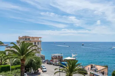 a street with palm trees and a building next to the ocean at Nice Absea le Port 1 in Nice