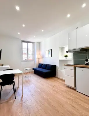a living room with a blue couch and a table at Collet Résidence in Nice