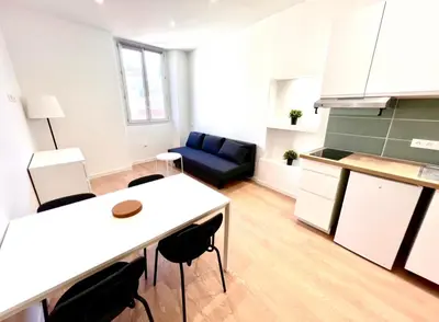 a kitchen and a living room with a table and chairs at Collet Résidence in Nice
