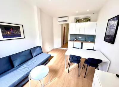 a living room with a blue couch and a table and chairs at Collet Résidence in Nice