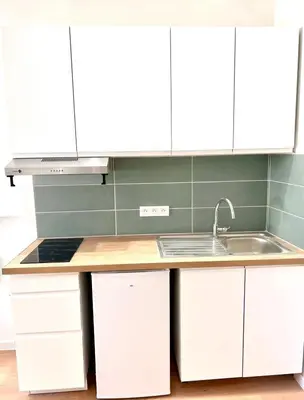 a kitchen with white cabinets and a sink at Collet Résidence in Nice