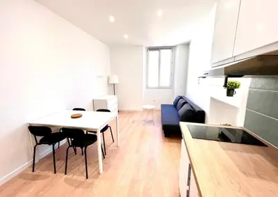 a kitchen and living room with a table and chairs at Collet Résidence in Nice