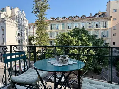 a table and chairs on a balcony with a building at Appartement niçois au coeur du triangle d'or in Nice