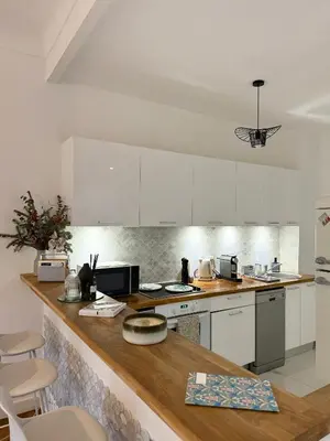 a kitchen with white cabinets and a wooden counter top at Appartement niçois au coeur du triangle d'or in Nice