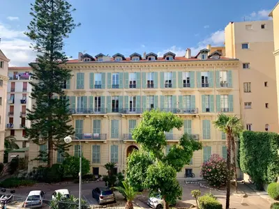 a large building with cars parked in a parking lot at Appartement niçois au coeur du triangle d'or in Nice