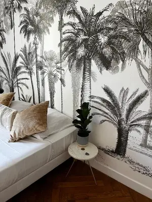 a bedroom with a bed with palm trees on the wall at Appartement niçois au coeur du triangle d'or in Nice