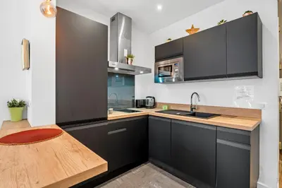 a kitchen with black cabinets and a wooden counter top at Nice Renting - ROSSETTI - Modern Haven Heart of Old Nice in Nice