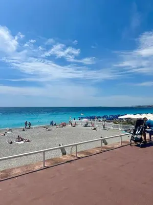 a beach with people laying on the sand and the ocean at Appartement neuf et rénové promenade des anglais in Nice